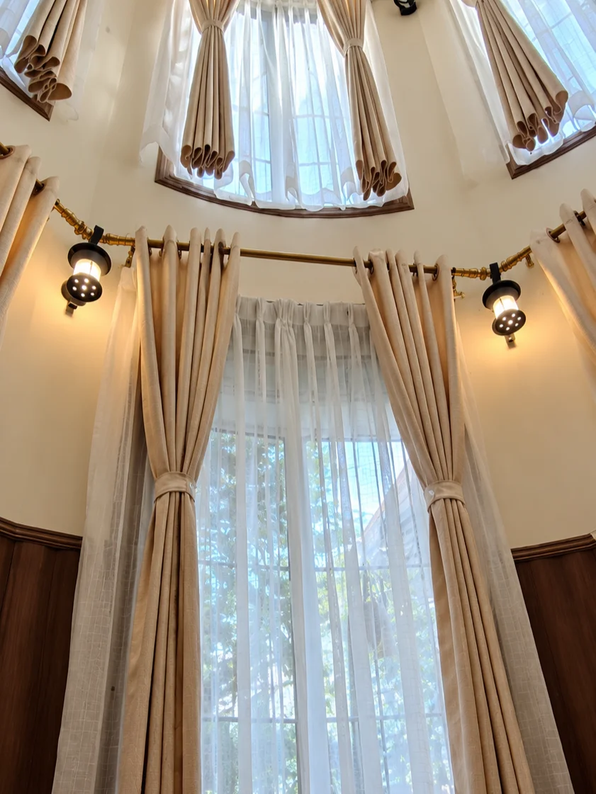 Elegant Multi-Level Bay Windows with Layered Beige Draperies and Sheer Curtains